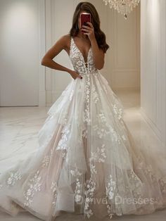 a woman taking a selfie wearing a wedding dress with white flowers on the skirt