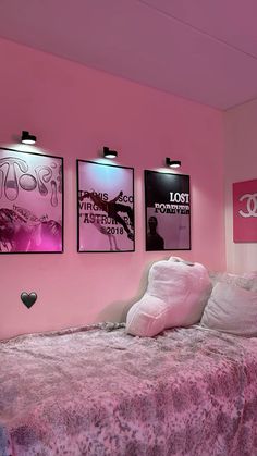 a bedroom with pink walls and posters on the wall above the bed, along with a stuffed animal