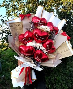 a bouquet of chocolates wrapped in paper and tied with ribbon is held by a man