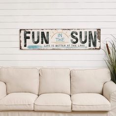 a white couch sitting next to a wooden sign that says fun in the sun life is better at the lake