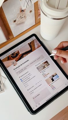 a person is using a tablet on a desk with pictures and a coffee cup in the background