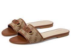 GUESS Hammi - Women's Sandals : Cognac : Display your love for modern aesthetics while adding an iconic touch to your look by opting for the GUESS Sandals which are versatile enough to be worn any day and everyday. Logo-printed fabric and faux leather upper with goldtone iconic logo accent. Synthetic lining and insole. Slip-on style for easy on and off. Open round toe. Durable and flexible synthetic rubber outsole. Imported. Designer Sandals With Leather Trim For Summer, Luxury Leather Trim Sandals For Summer, Luxury Sandals With Leather Trim For Summer, Open Toe Sandals With Logo For Spring, Logo Slip-on Sandals For Summer, Spring Open Toe Sandals With Logo, Flat Sandals With Logo For Summer, Summer Slip-on Sandals With Logo, Spring Season Open Toe Sandals With Logo