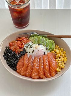 a white plate topped with sushi and vegetables next to a drink