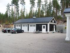 two cars parked in front of a small black and white building with a metal roof