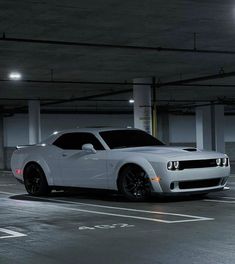 a white sports car parked in a parking garage with no one around it at night