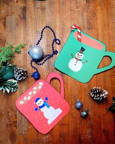 two snowman themed placemats sitting on top of a wooden table next to christmas decorations