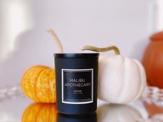 a candle sitting on top of a table next to pumpkins