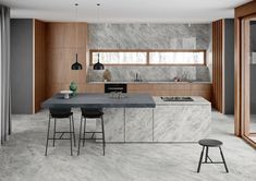 a kitchen with marble counter tops and stools in front of an open floor plan