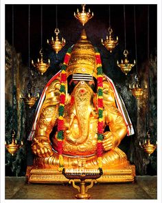 the statue of lord ganesha is gold and decorated with garlands on its head