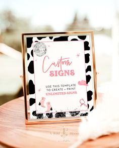 a pink and black sign sitting on top of a wooden table