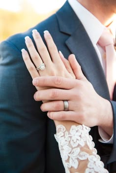 a bride and groom holding each other's hands with their wedding rings on their fingers