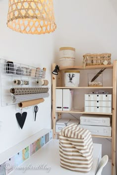 a white desk topped with lots of drawers and shelves next to a light hanging from the ceiling