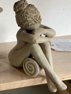 a clay sculpture sitting on top of a wooden table