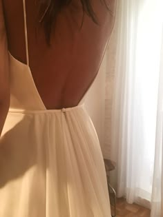 the back of a woman's white dress in front of a window