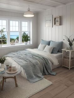 a bedroom with white walls and wood flooring has a large window overlooking the ocean