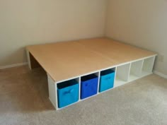 an empty room with three blue bins on the floor and a shelf in the corner