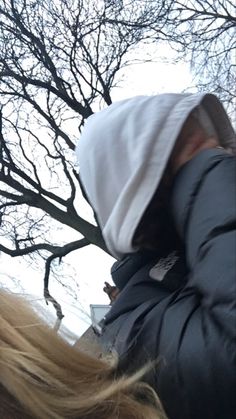 a person wearing a white hat and jacket with trees in the back ground behind them