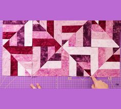 someone is making a quilt with pink and white squares on purple paper next to scissors