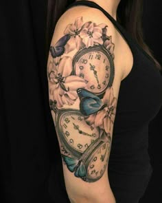 a woman's arm with a clock and flowers tattooed on the back of it