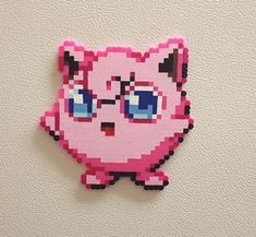 an image of a pink cat with blue eyes on a white wall in the shape of a pixel art piece