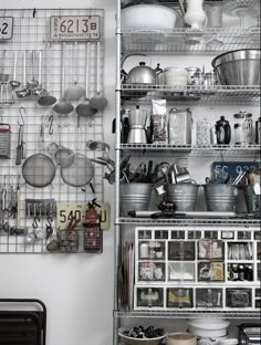 an organized kitchen with pots, pans and utensils hanging on the wall