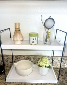 there is a shelf with bowls and utensils on it next to a vase