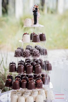 a tiered cake with chocolate covered desserts on it and a bride and groom figurine