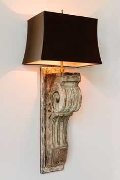 a wall lamp with a black shade on it's side against a white wall