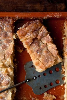 several pieces of cake on a pan with a spatula in it and powdered sugar over the top