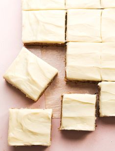 white frosted squares of cake sitting on top of a pink surface