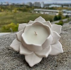 a white candle sitting on top of a rock