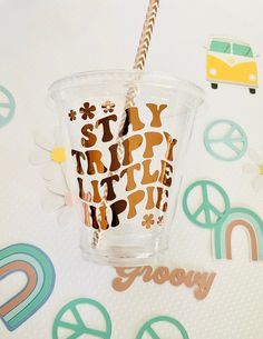 a plastic cup with a straw in it on a table next to peace signs and paper cutouts