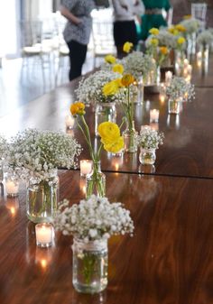 several vases filled with yellow and white flowers sitting on a table next to each other