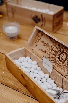 a wooden box filled with white rocks and spoons on top of a wood table