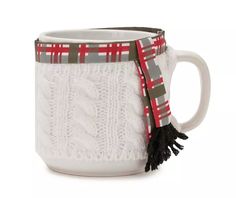 a white coffee mug with a red and gray plaid scarf around it's handle