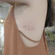 the back of a woman's shoulder with three small stars and planets on it