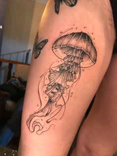 a woman's leg with tattoos on it and a butterfly flying over the jellyfish