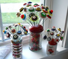 two vases filled with assorted buttons sitting on a window sill