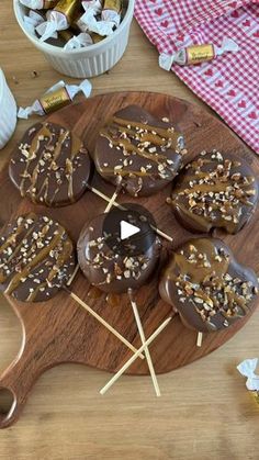 chocolate covered donuts with sprinkles on a wooden platter next to a bowl of candy