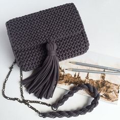 a gray crocheted purse sitting on top of a table next to a book