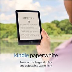 a woman holding an electronic device in her hand with the caption kindle paperwhitte now with a larger display and adjustable warm light