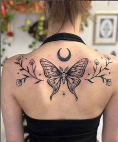 the back of a woman's shoulder with a butterfly and moon tattoo on it