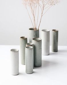 four vases with branches in them on a table top next to each other and one is empty