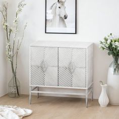 a white cabinet sitting next to a vase filled with flowers