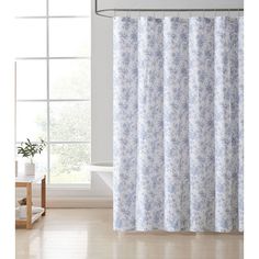 a shower curtain with blue and white flowers on it in a clean room next to a window