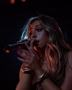 a woman with long hair holding a microphone in her hand and singing into the microphone