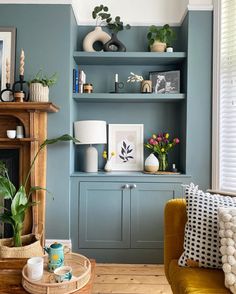 a living room with blue walls and shelves filled with potted plants on top of them