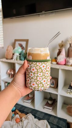 a person holding up a cup with a straw in it on top of a table