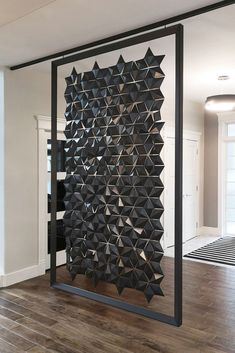 a room divider made out of black paper with geometric shapes on the wall and wood flooring