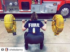 a firefighter squats down with two large yellow hoses in front of her